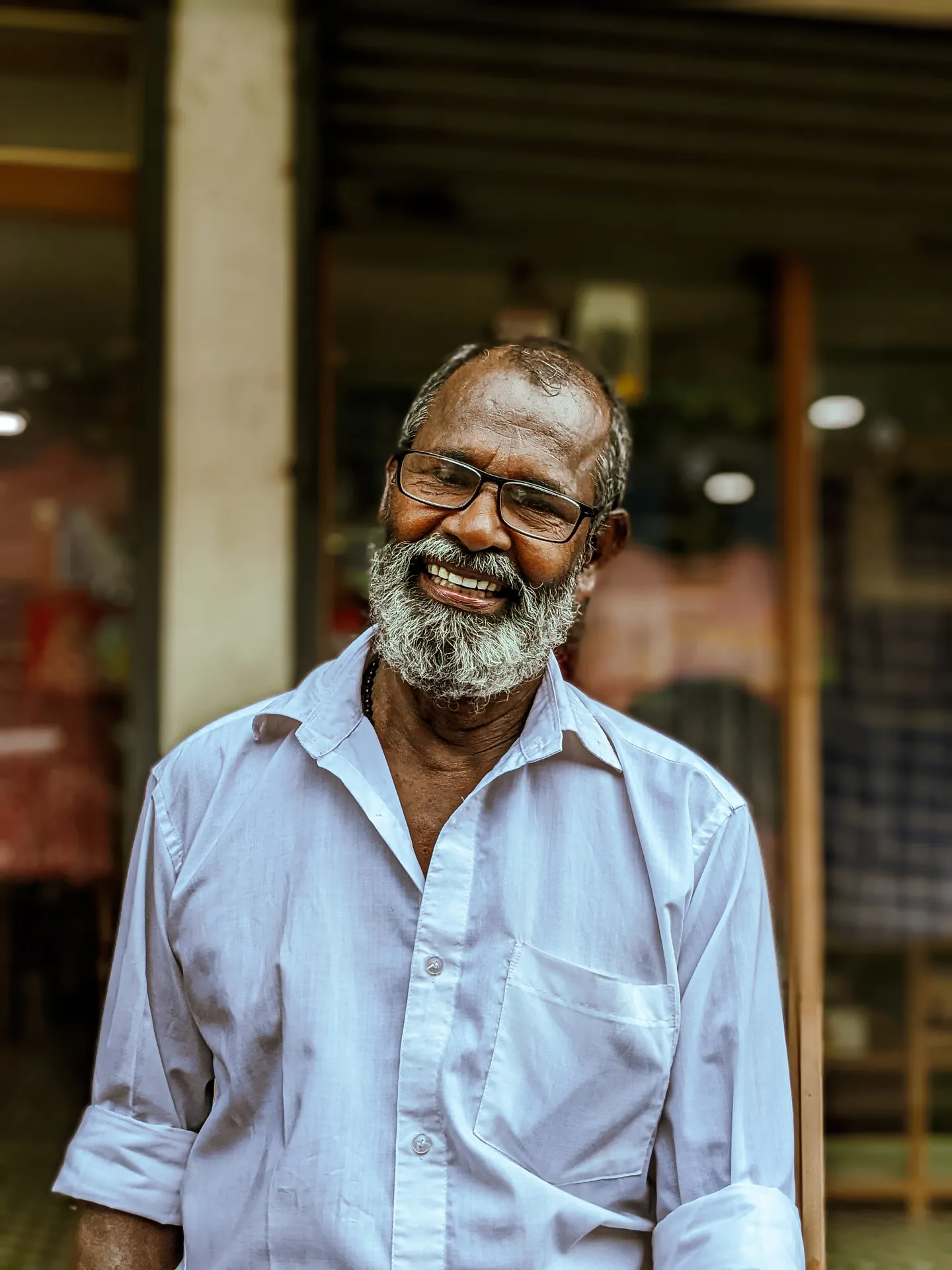 Retrato provisional de un hombre sonriente con barba gris, gafas y camisa clara.